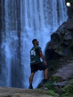 Homem em frente a uma cachoeira alta