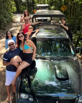 Grupo sentado no capô da caminhonete na trilha