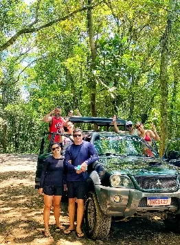 Guia e turistas sorrindo ao lado da caminhonete 4x4
