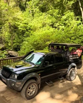 Caminhonete 4x4 com grupo na caçamba em ponte de madeira