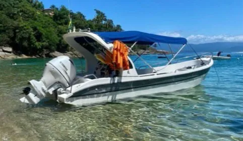 Lancha com toldo azul ancorada em água transparente
